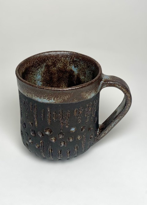 Taza pasta negra. Interior y bajorelieve azul moteado. Exterior pasta expuesta